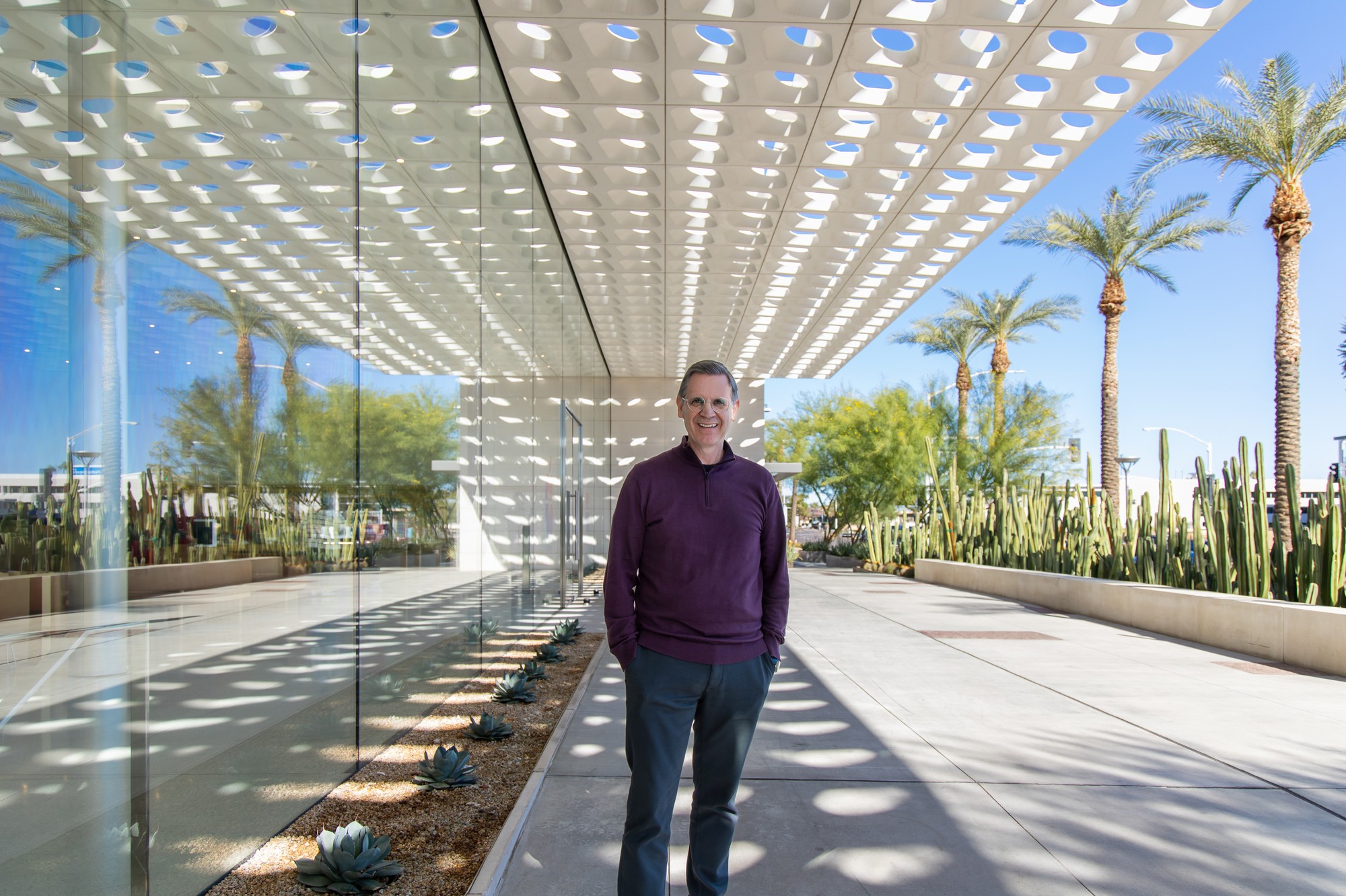 Charles Sidi standing beneath a patterned canopy outside a modern glass building